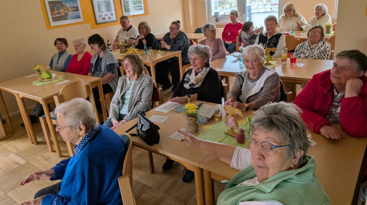 Viele Personen sitzen an Tischen und hören den Musikerinnen zu.